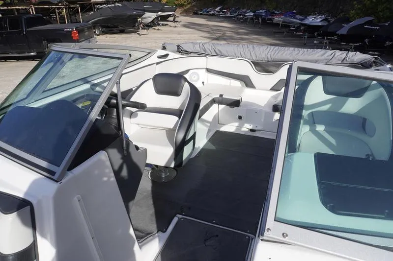 Slide: The Image of 2015 Yamaha Boats SX210 interior with seating and windshield, parked outdoors. - 15