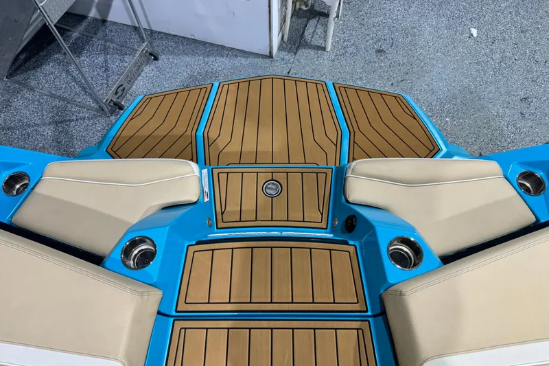 Slide: The Image of 2023 Nautique Super Air Nautique S23 boat deck with teak flooring and beige seating. - 14