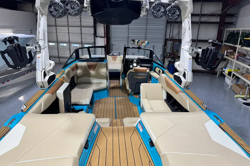 Slide: The Image of 2023 Nautique Super Air Nautique S23 interior with beige seating and blue accents in a garage. - 17