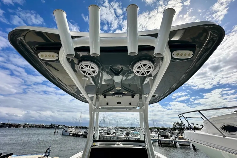 Slide: The Image of 2019 Tidewater 252 CC Adventure boat with rod holders and speakers, docked under a blue sky. - 45