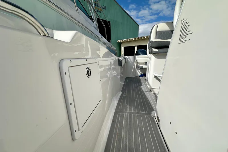 Slide: The Image of 2019 Tidewater 252 CC Adventure boat interior with seating and storage, docked near a marina. - 47