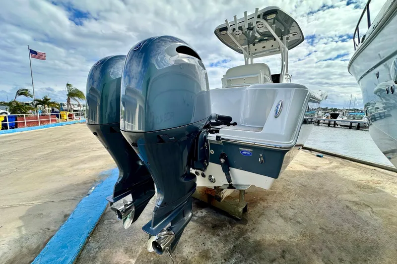 Slide: The Image of 2019 Tidewater 252 CC Adventure boat cruising on a sunny day near waterfront homes. - 6