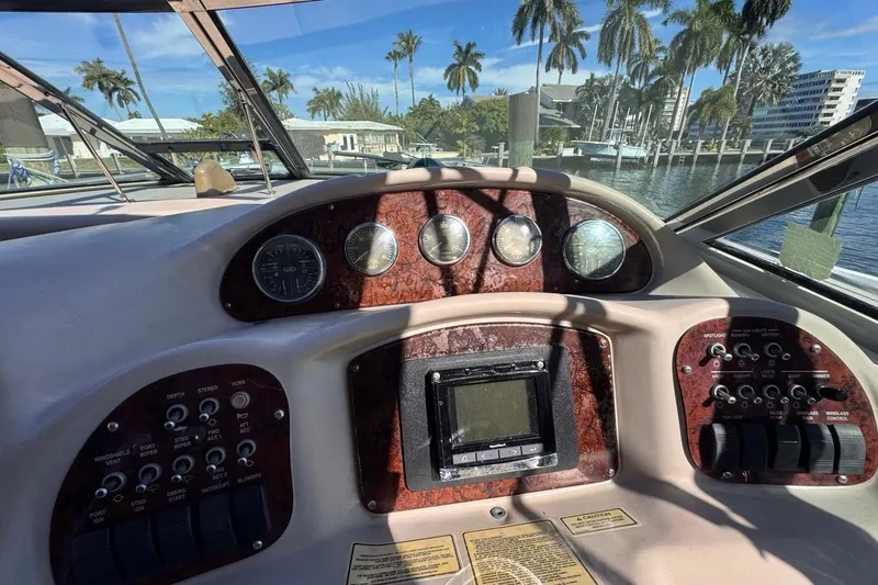 Slide: The Image of 2004 Sea Ray 340 Sundancer dashboard with gauges and controls, docked near palm trees. - 36
