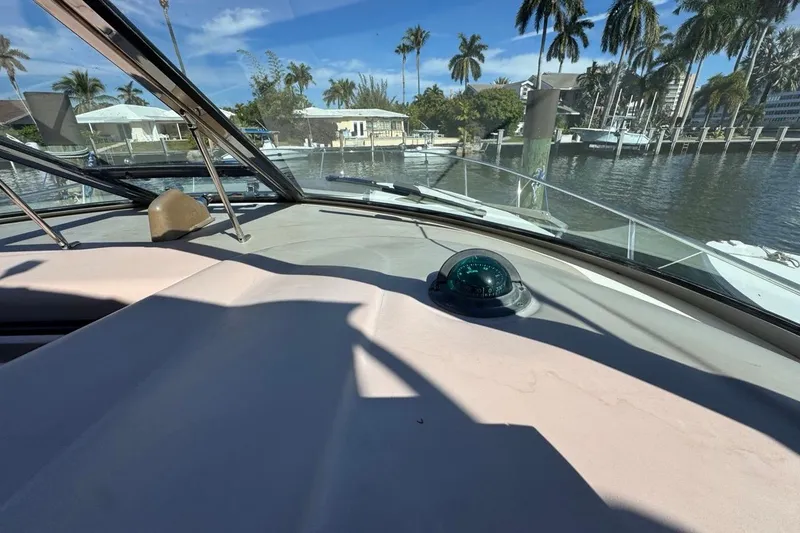 Slide: The Image of 2004 Sea Ray 340 Sundancer helm view with compass, docked near palm trees. - 38