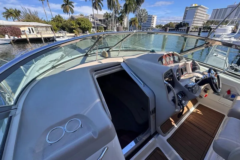 Slide: The Image of 2004 Sea Ray 340 Sundancer helm with modern controls, docked near palm trees and waterfront buildings. - 40