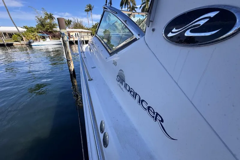Slide: The Image of 2004 Sea Ray 340 Sundancer yacht docked by waterfront homes, under clear blue sky. - 41