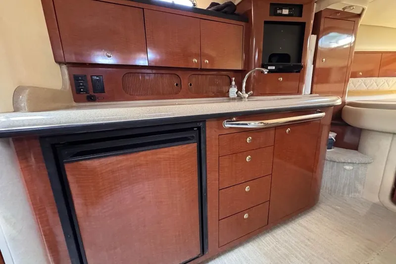 Slide: The Image of 2004 Sea Ray 340 Sundancer interior kitchen with wood cabinets and compact appliances. - 56