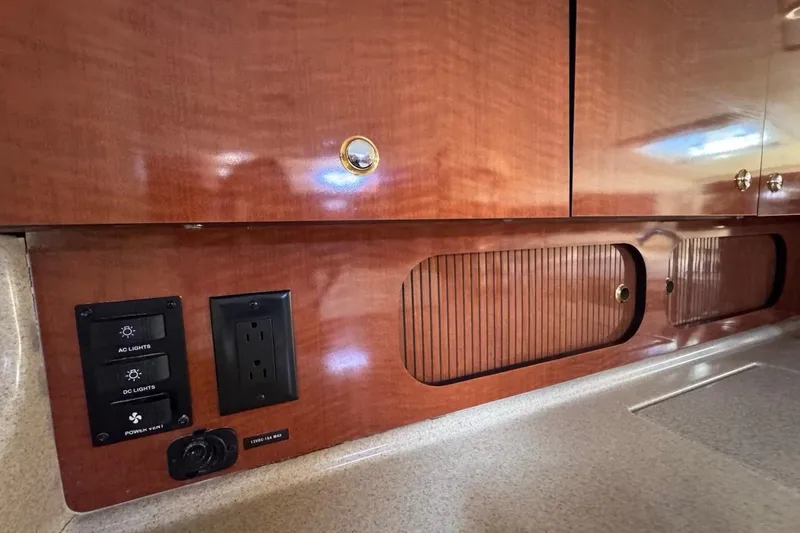Slide: The Image of 2004 Sea Ray 340 Sundancer interior with wood cabinetry, electrical outlets, and light switches. - 58