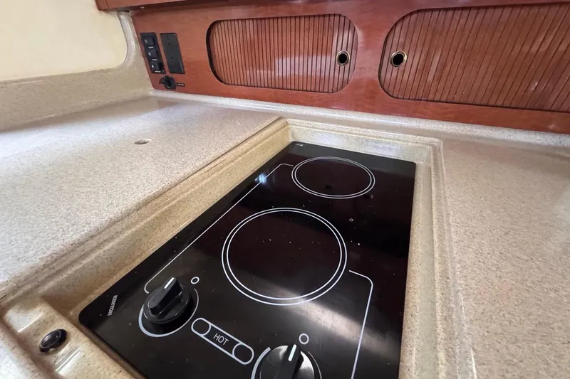 Slide: The Image of 2004 Sea Ray 340 Sundancer kitchen with electric stovetop and wooden cabinetry. - 59