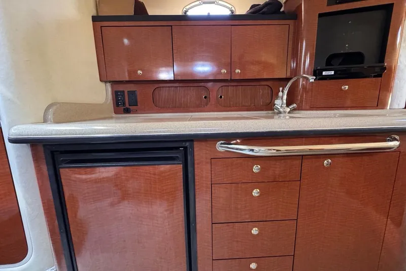 Slide: The Image of 2004 Sea Ray 340 Sundancer interior with wood cabinetry and compact kitchenette. - 77