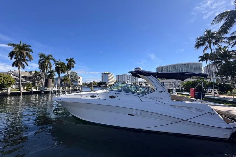 Slide: The Image of 2004 Sea Ray 340 Sundancer yacht docked by palm trees and waterfront buildings. - 91