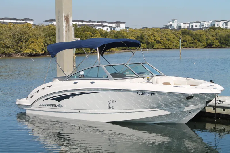 The Image of 2015 Chaparral 224 Sunesta boat docked on calm water with blue canopy. - 13