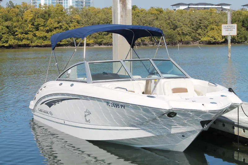 Slide: The Image of 2015 Chaparral 224 Sunesta boat docked on calm water with blue canopy. - 14