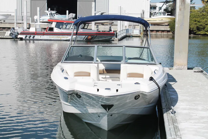 Slide: The Image of 2015 Chaparral 224 Sunesta boat docked at marina, featuring sleek design and blue canopy. - 17