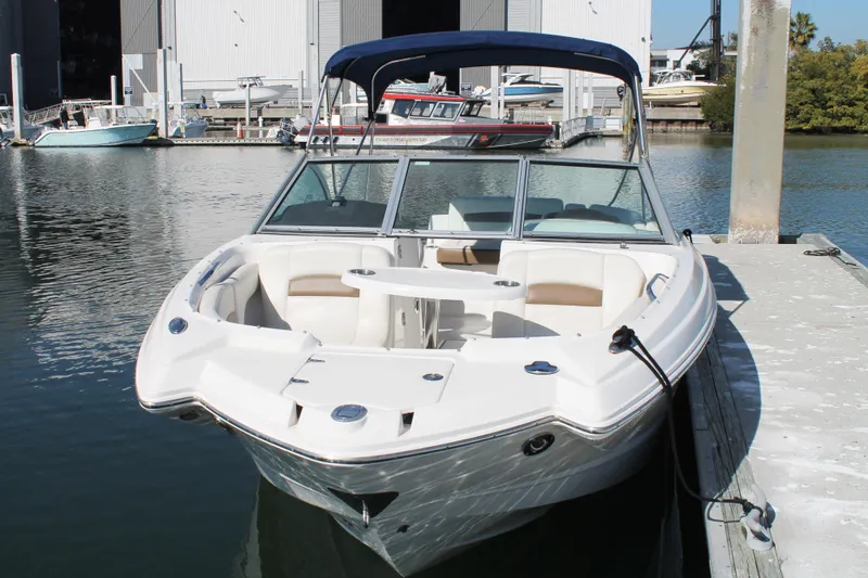 Slide: The Image of 2015 Chaparral 224 Sunesta boat docked at marina, featuring spacious seating and canopy. - 18