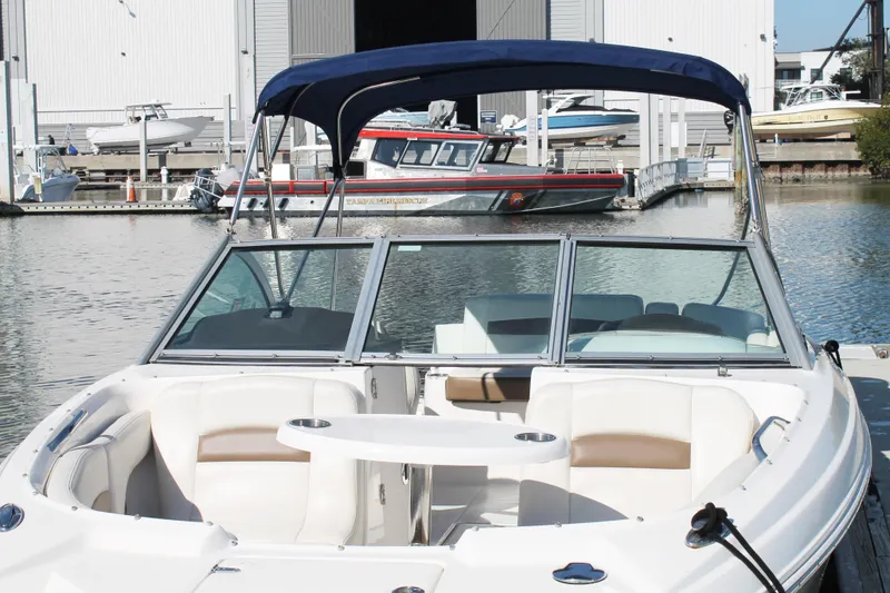 Slide: The Image of 2015 Chaparral 224 Sunesta boat docked with blue canopy and spacious seating. - 21
