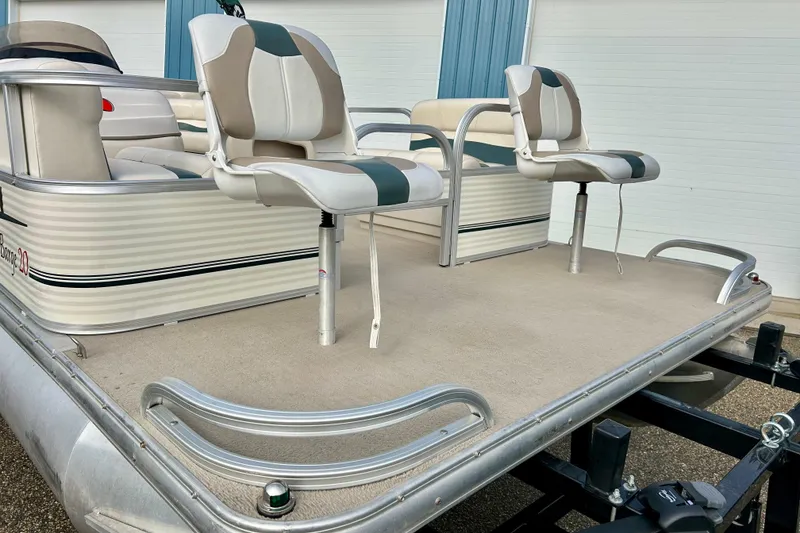 Slide: The Image of 2010 Sun Tracker Party Barge 20 Classic Series with seating, docked on trailer. - 11