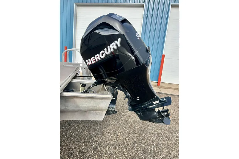 Slide: The Image of 2010 Sun Tracker Party Barge 20 with Mercury outboard motor, parked near blue building. - 7