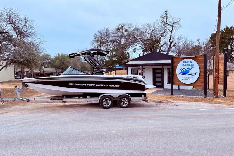 The Image of 2010 Nautique Super Air Nautique 210 boat on trailer outside Elite Marine shop. - 1
