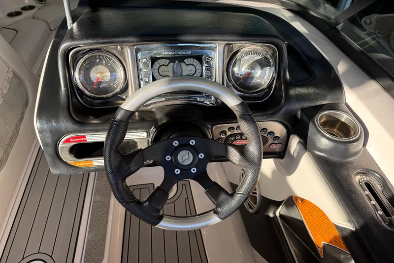 Slide: The Image of 2010 Nautique Super Air Nautique 210 boat docked under covered marina. - 23