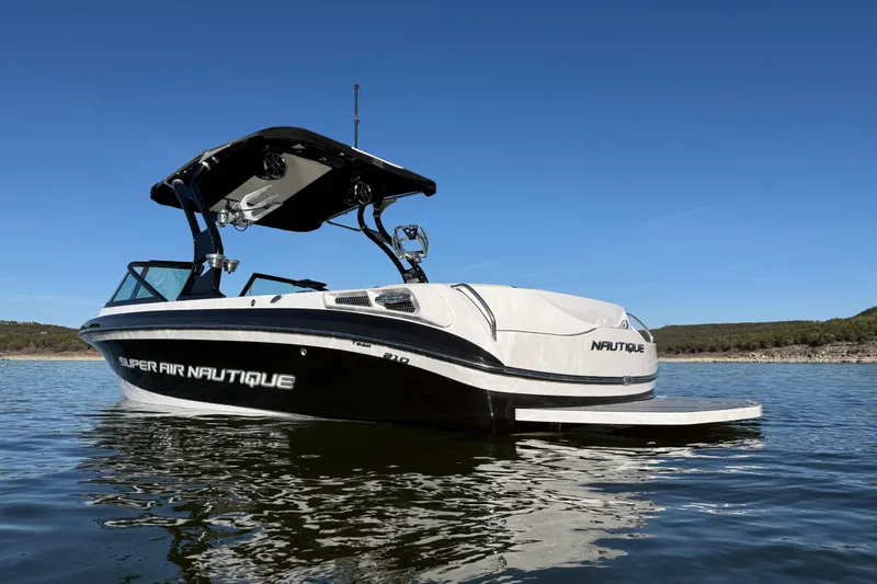 Slide: The Image of 2010 Nautique Super Air Nautique 210 boat on calm water under clear blue sky. - 3