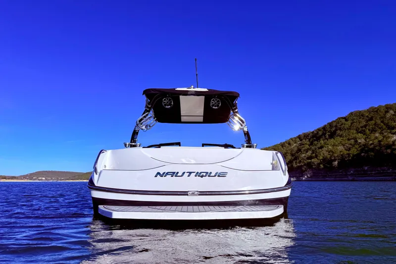 Slide: The Image of 2010 Nautique Super Air Nautique 210 boat on water, clear blue sky background. - 4
