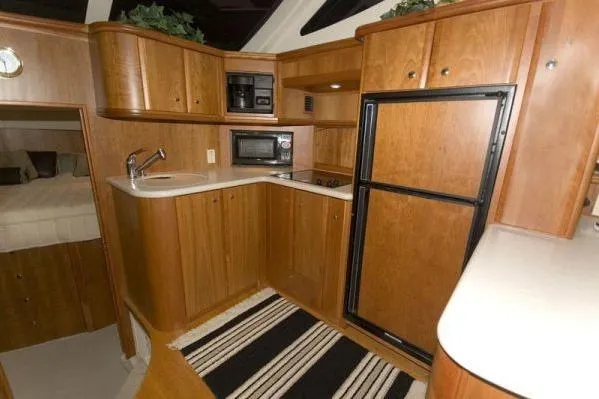 Slide: The Image of 2003 Silverton 39 Motor Yacht kitchen with wood cabinetry, appliances, and striped rug. - 14