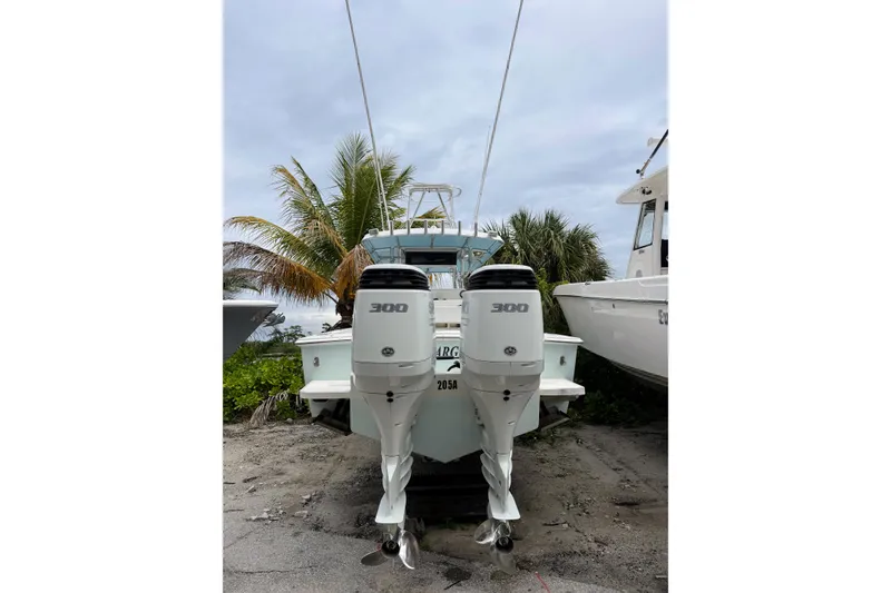 Slide: The Image of 2005 Jupiter 31 Center Console boat with twin 300 horsepower engines, parked near palm trees. - 2