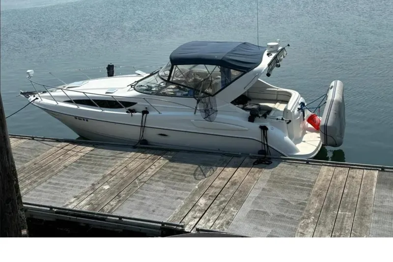 The Image of 2002 Bayliner 3055 Ciera docked at a marina, featuring a sleek design and blue canopy. - 0