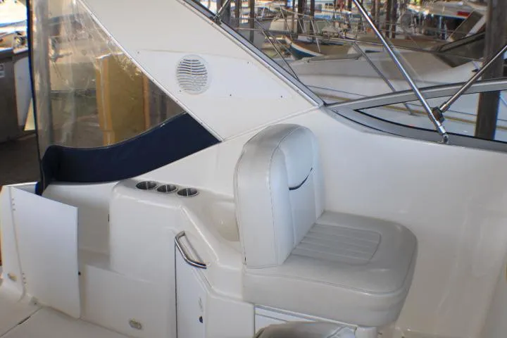 Slide: The Image of 2002 Bayliner 3055 Ciera boat interior with white seating and dock view. - 12