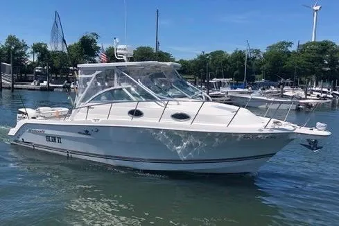 The Image of 2004 Wellcraft 290 Coastal boat docked in a marina, surrounded by calm water. - 0
