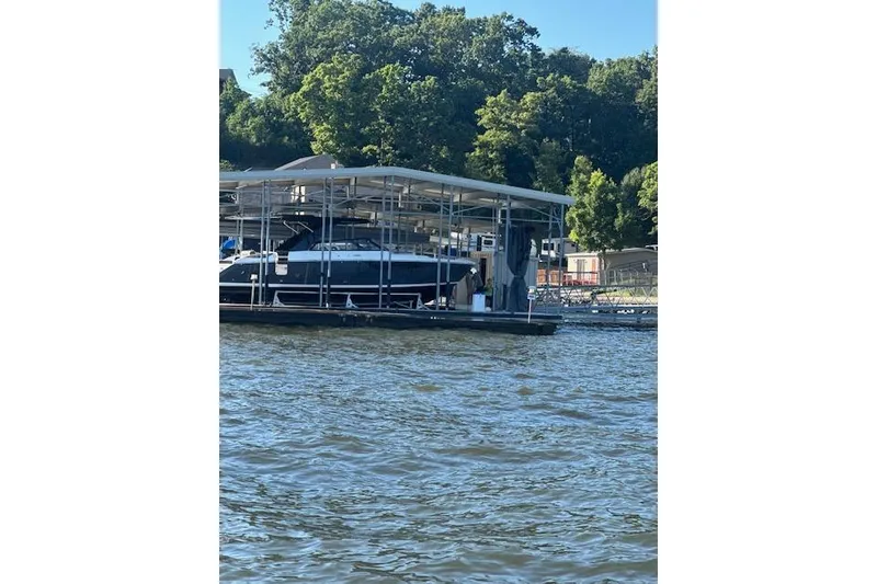 Slide: The Image of 2025 Cobalt R35 boat docked on a sunny day, surrounded by lush greenery. - 16
