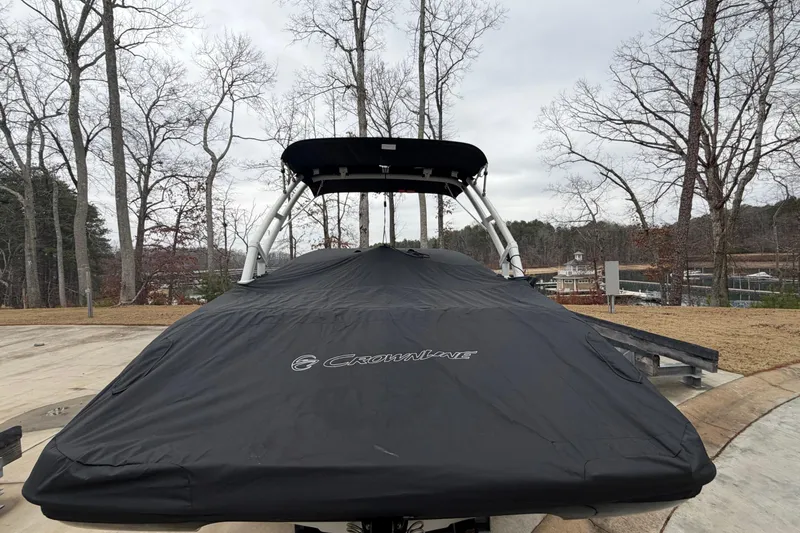 Slide: The Image of 2022 Crownline 240 SS boat covered, parked outdoors in a wooded area. - 18