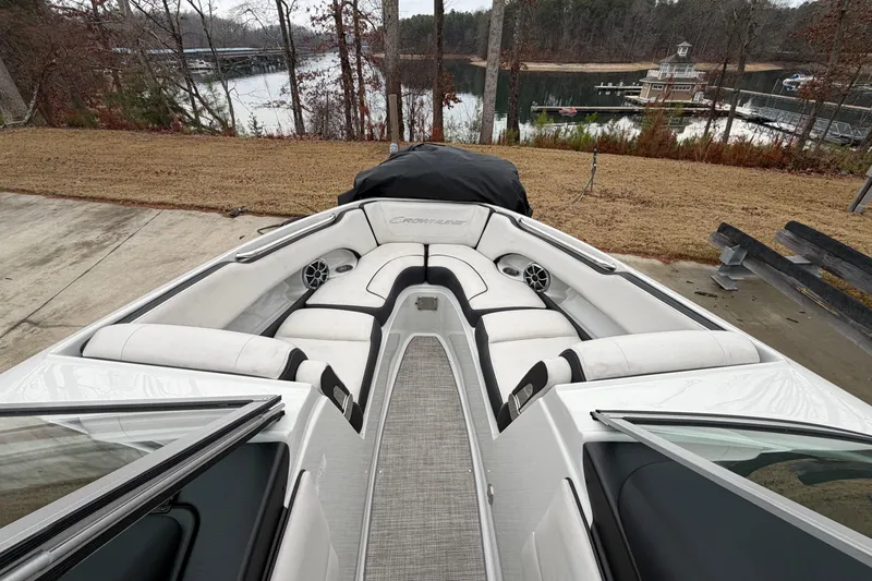 Slide: The Image of 2022 Crownline 240 SS boat with white seating, docked near a serene lake. - 5