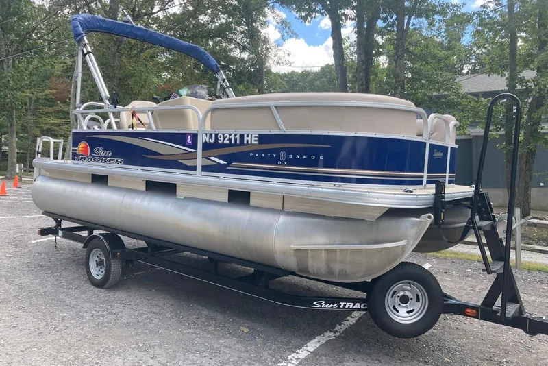 Slide: The Image of 2014 Sun Tracker Party Barge 18 DLX pontoon boat on trailer in wooded area. - 2