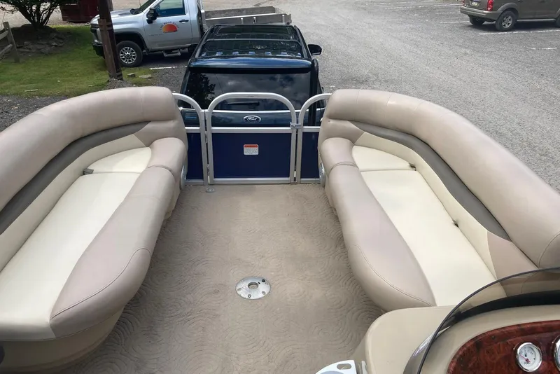 Slide: The Image of 2014 Sun Tracker Party Barge 18 DLX with beige seating, parked on gravel. - 5