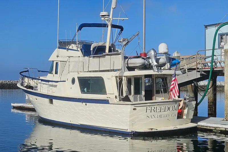 Slide: The Image of 1976 Hatteras 48 Long Range Cruiser in marina, clear blue sky background. - 2