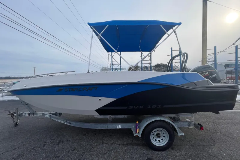 The Image of 2026 Starcraft SVX 191 OB boat on trailer with blue canopy. - 0