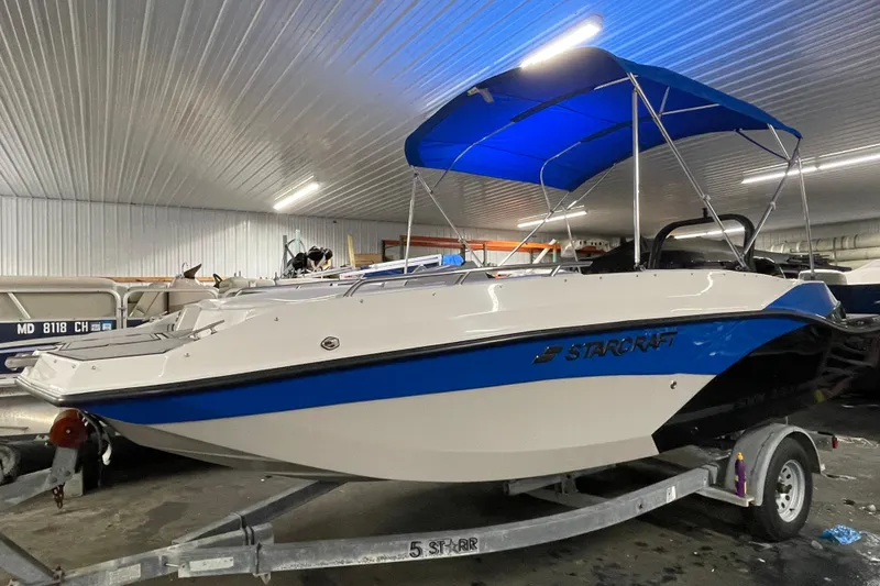 Slide: The Image of 2026 Starcraft SVX 191 OB boat with blue canopy in warehouse. - 14