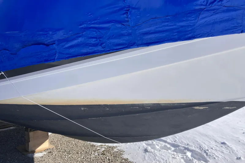Slide: The Image of 2001 Formula 37 Performance Cruiser hull with blue tarp cover, resting on wooden blocks. - 12
