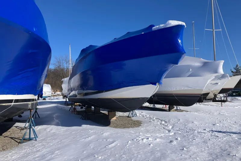 Slide: The Image of 2001 Formula 37 Performance Cruiser boats covered in blue tarps, stored on stands in snowy yard. - 68