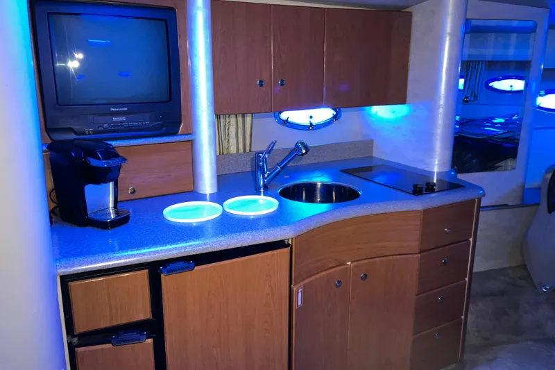 Slide: The Image of 2001 Formula 37 Performance Cruiser interior kitchen with sink, stove, and TV under blue lighting. - 21
