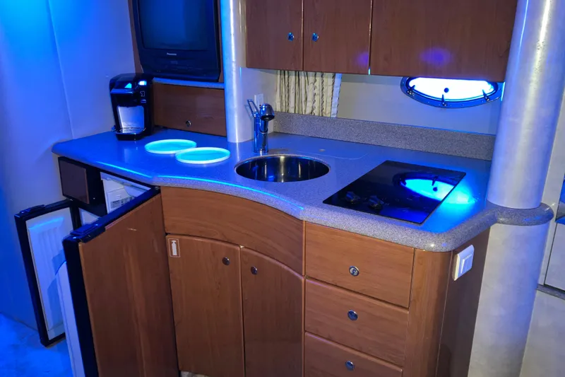Slide: The Image of 2001 Formula 37 Performance Cruiser kitchen with sink, stove, and cabinets under blue lighting. - 19