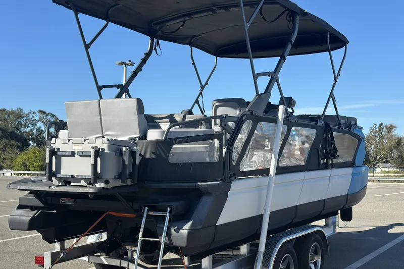 Slide: The Image of 2022 Sea-Doo Switch Sport 21 pontoon boat on trailer, featuring spacious seating and canopy. - 2
