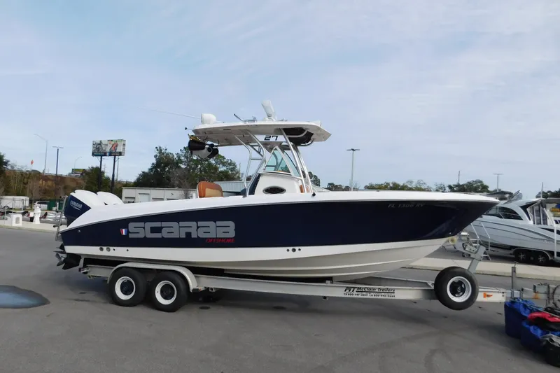 The Image of 2008 Wellcraft 27 Scarab Tournament boat on trailer, parked outdoors. - 0
