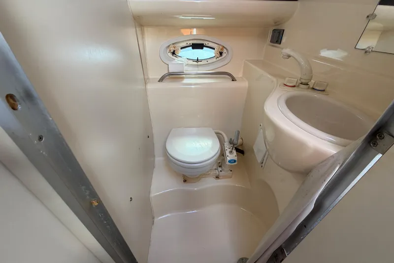 Slide: The Image of 2003 Bayliner 2855 Ciera boat bathroom with toilet, sink, and porthole window. - 33