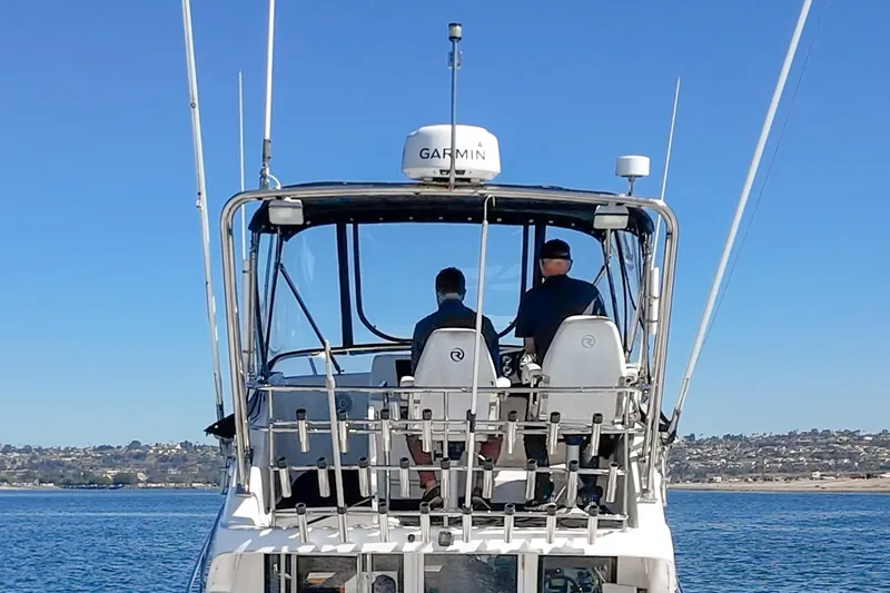 Slide: The Image of 2006 Riviera 33 Flybridge boat with two people navigating on a sunny day. - 14