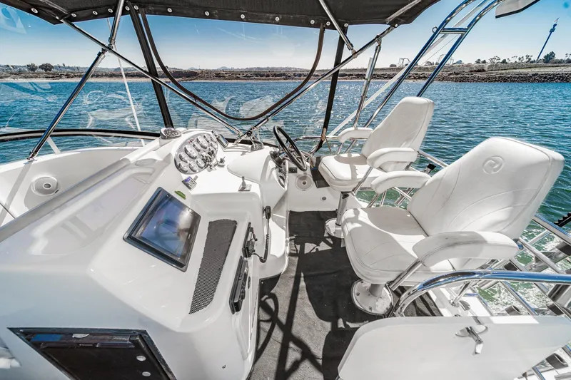 Slide: The Image of 2006 Riviera 33 Flybridge boat interior with helm, steering wheel, and white captain chairs. - 15