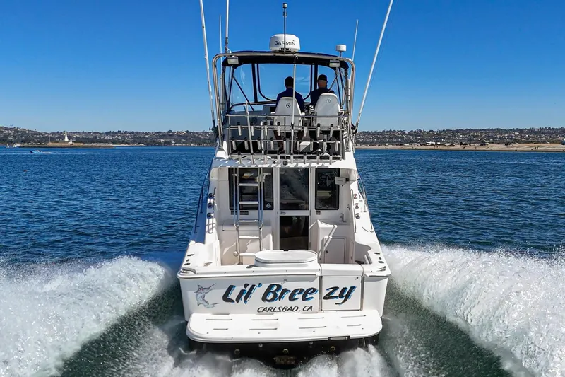 Slide: The Image of 2006 Riviera 33 Flybridge boat cruising on open water, rear view. - 21