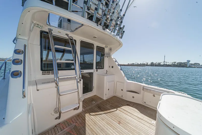 Slide: The Image of 2006 Riviera 33 Flybridge yacht deck with ladder, overlooking serene water and distant shoreline. - 22